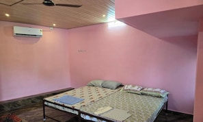 A bedroom with a bed, pillows, a blanket, a wooden ceiling, and an air conditioning unit.