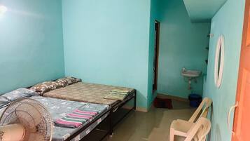 Una habitación con cama, ventilador, lavamanos y espejo.