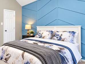 A bedroom with a bed, a nightstand with a lamp, and a door. - Big Groups, Game Room, BBQ, Pet Friendly, Pool (Frisco)