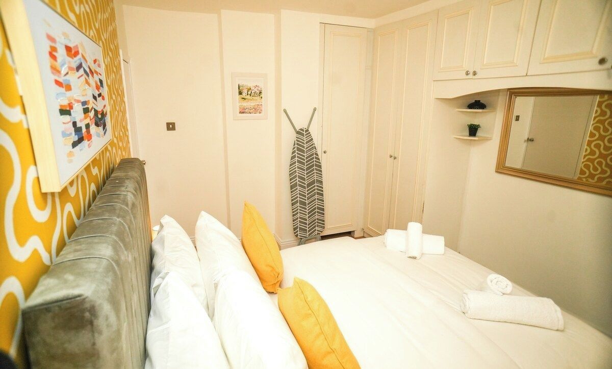 A hotel room with a bed, a gray sofa, a mirror, and a door.