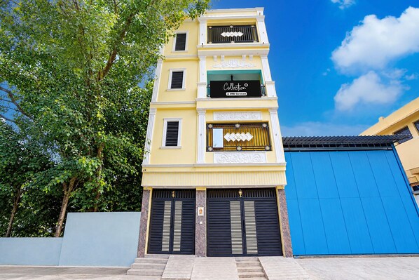 A multi-story building with a yellow facade, black shutters, and a blue garage door.