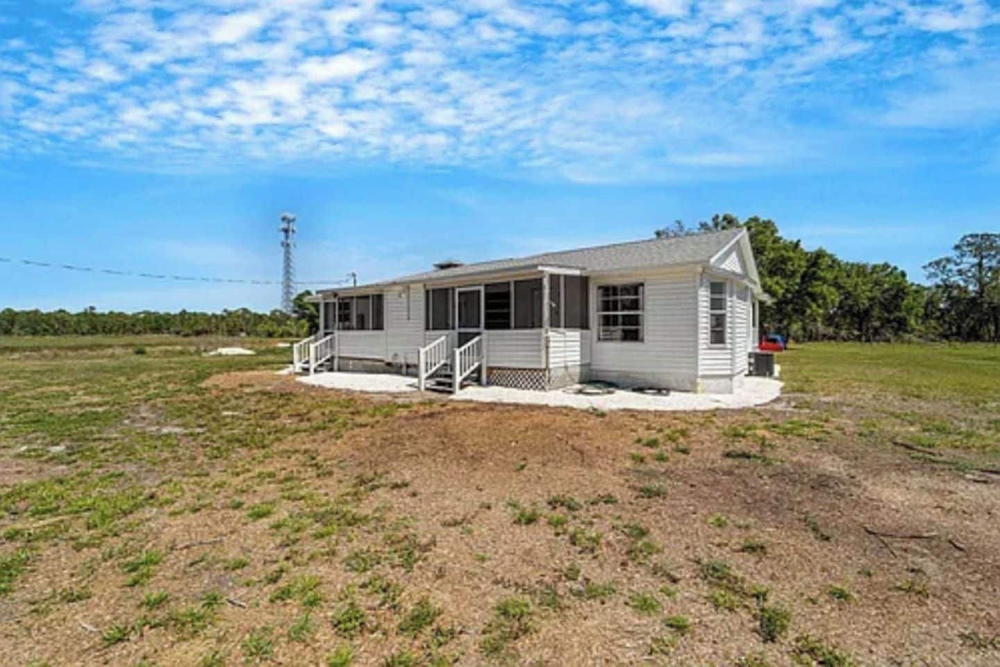 Einbungalow mit Veranda, einem umzäunten Garten und blauem Himmel.