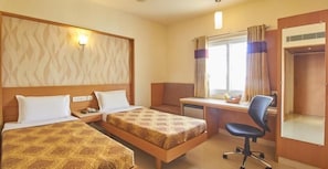Ein Hotelzimmer mit zwei Betten, einem Schreibtisch, einem Stuhl und einem Kleiderschrank.