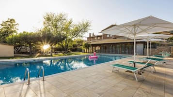 Piscina con un galleggiante a forma di fenicottero, patio soleggiato e poltrone da relax.