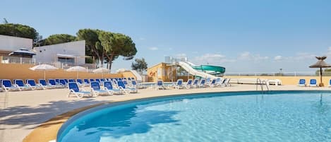 A swimming pool with lounge chairs and a water slide.