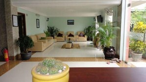 Un amplio salón con un conjunto de sofás, una mesa de centro y plantas en macetas.