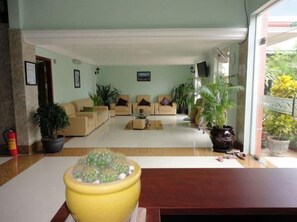 Un amplio salón con un conjunto de sofás, una mesa de centro y plantas en macetas.