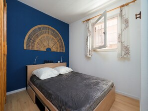A bedroom with a bed, a wall-mounted decorative item, a window with curtains, and a wooden floor. - Family Apartment for 6 in Les Deux Alpes (Le Grau-Du-Roi)