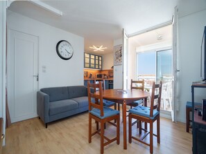 A living room with a sofa, dining table, and chairs, a kitchen in the background, and a balcony with a view. - Family Apartment for 6 in Les Deux Alpes (Le Grau-Du-Roi)