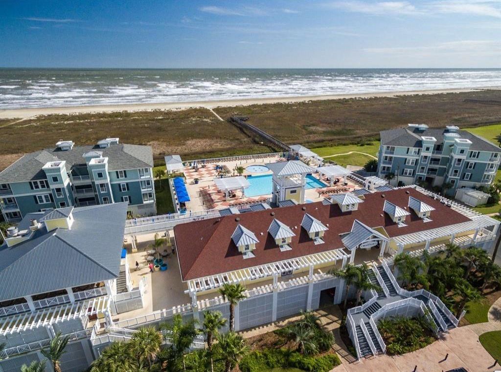 A beachfront hotel with multiple buildings, a swimming pool, and a boardwalk.