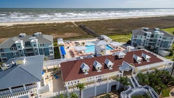A beachfront hotel with multiple buildings, a swimming pool, and a boardwalk.