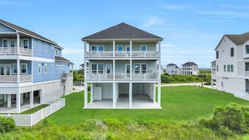 A two-story residential building with a balcony on the upper floor, surrounded by a well-maintained lawn.