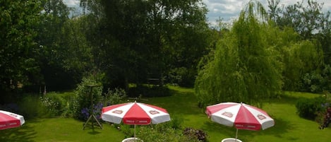 An outdoor seating area with tables and chairs, surrounded by lush greenery and trees.