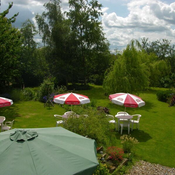 An outdoor seating area with tables and chairs, surrounded by lush greenery and trees.