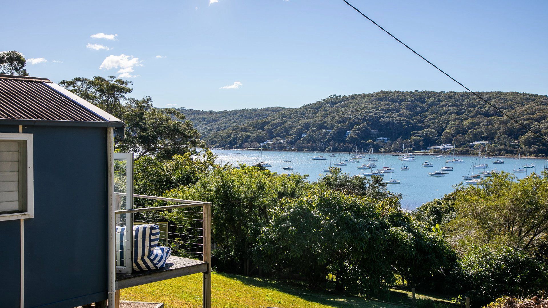 Une vue d’une zone côtière avec une maison surplombant une baie remplie de bateaux.