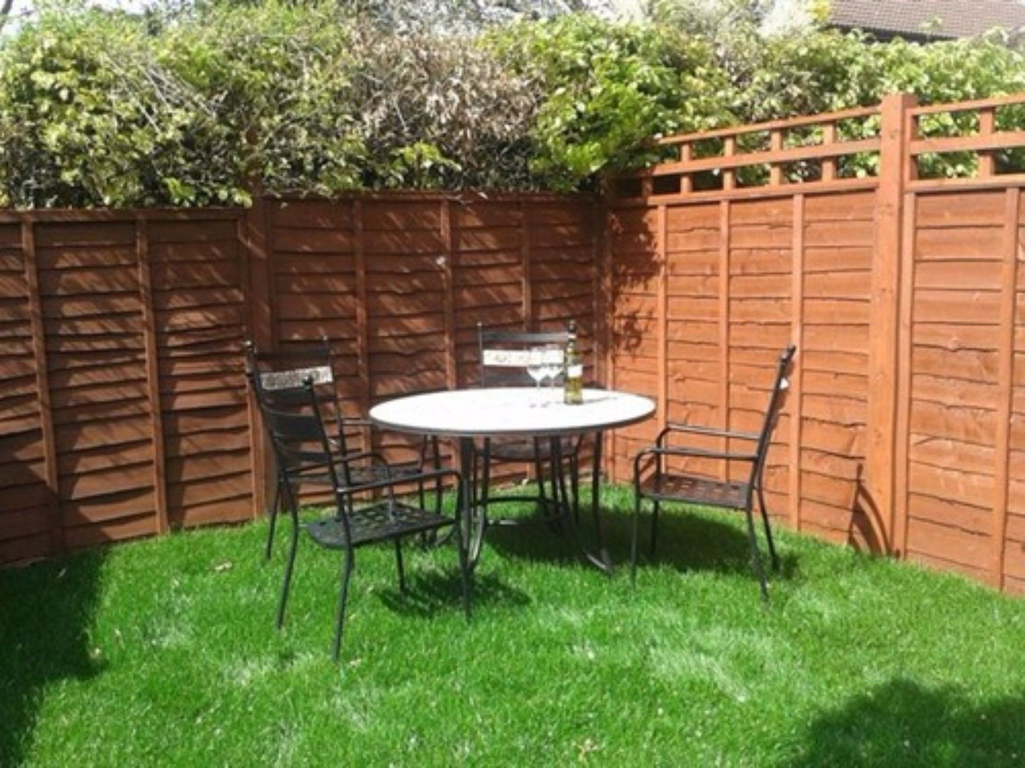 A fenced backyard with a round table and four chairs.