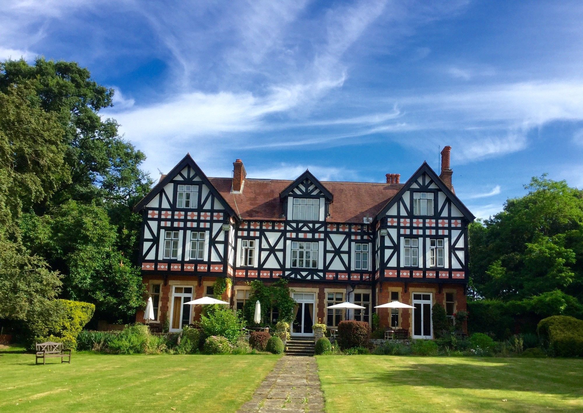 A Tudor-style building with a symmetrical facade, multiple windows, and a central entrance.