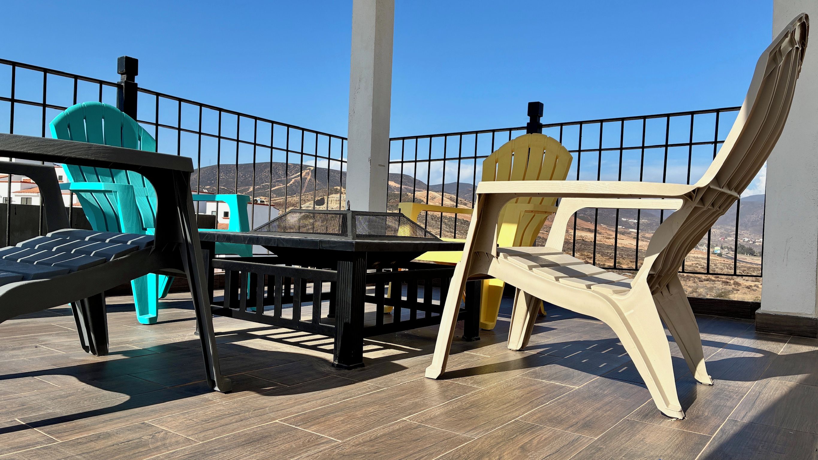 A terrace with a table and chairs, a railing, and a view of the landscape.