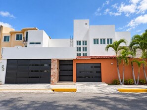 A modern building with two garage doors, a stone column, and a red-tiled roof. - Jounieh House | Unique, Spacious Home with Private Pool (Cozumel)
