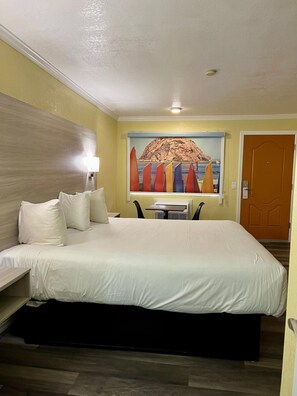 Una habitación de hotel con una cama grande, un escritorio y un cuadro de veleros en la pared.