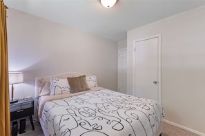 A bedroom with a bed, a desk, and a door.