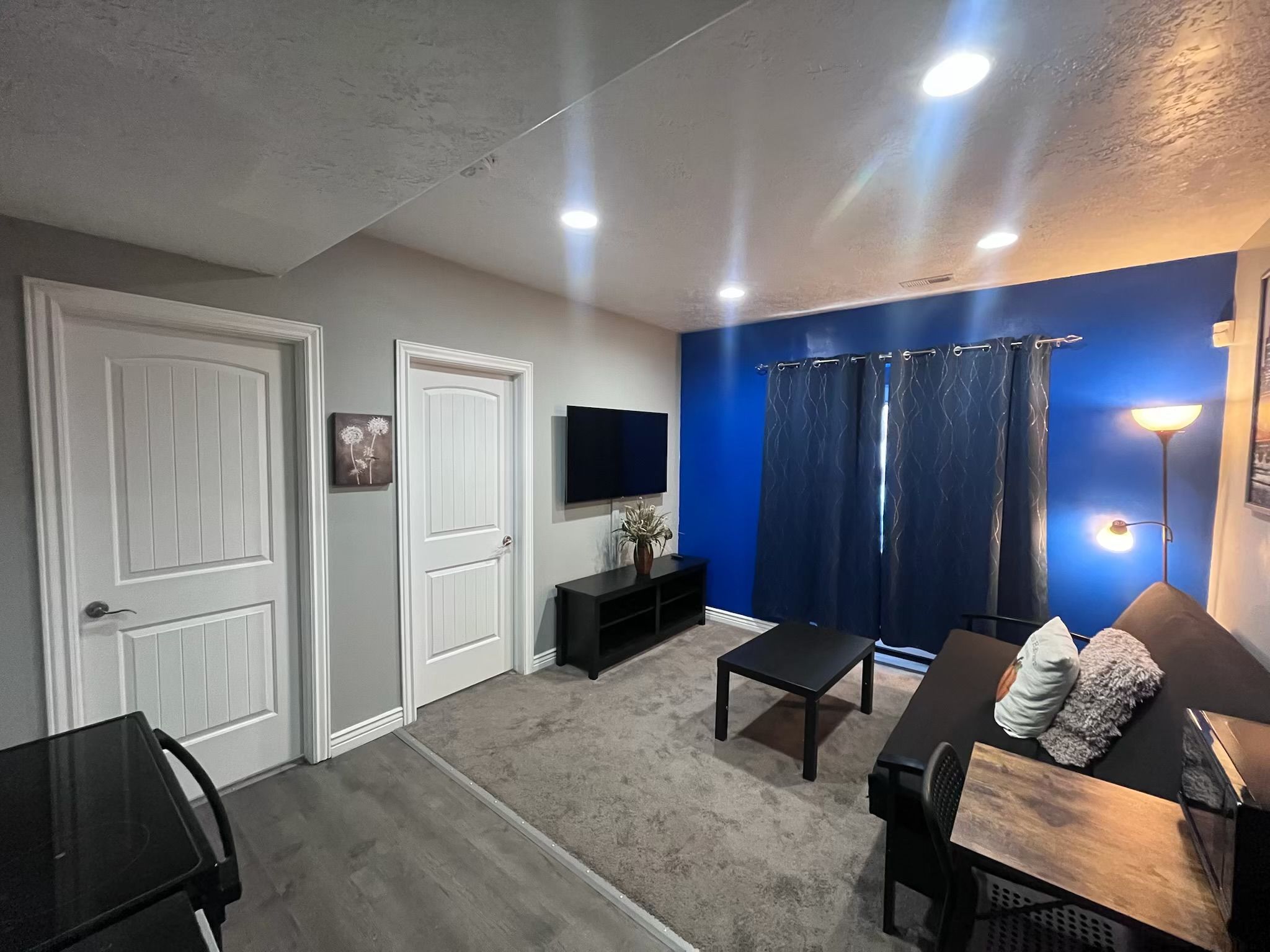 Ein Wohnzimmer mit Fernseher, Sofa, Couchtisch und einer blauen Akzentwand.