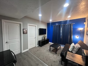 Ein Wohnzimmer mit Fernseher, Sofa, Couchtisch und einer blauen Akzentwand.