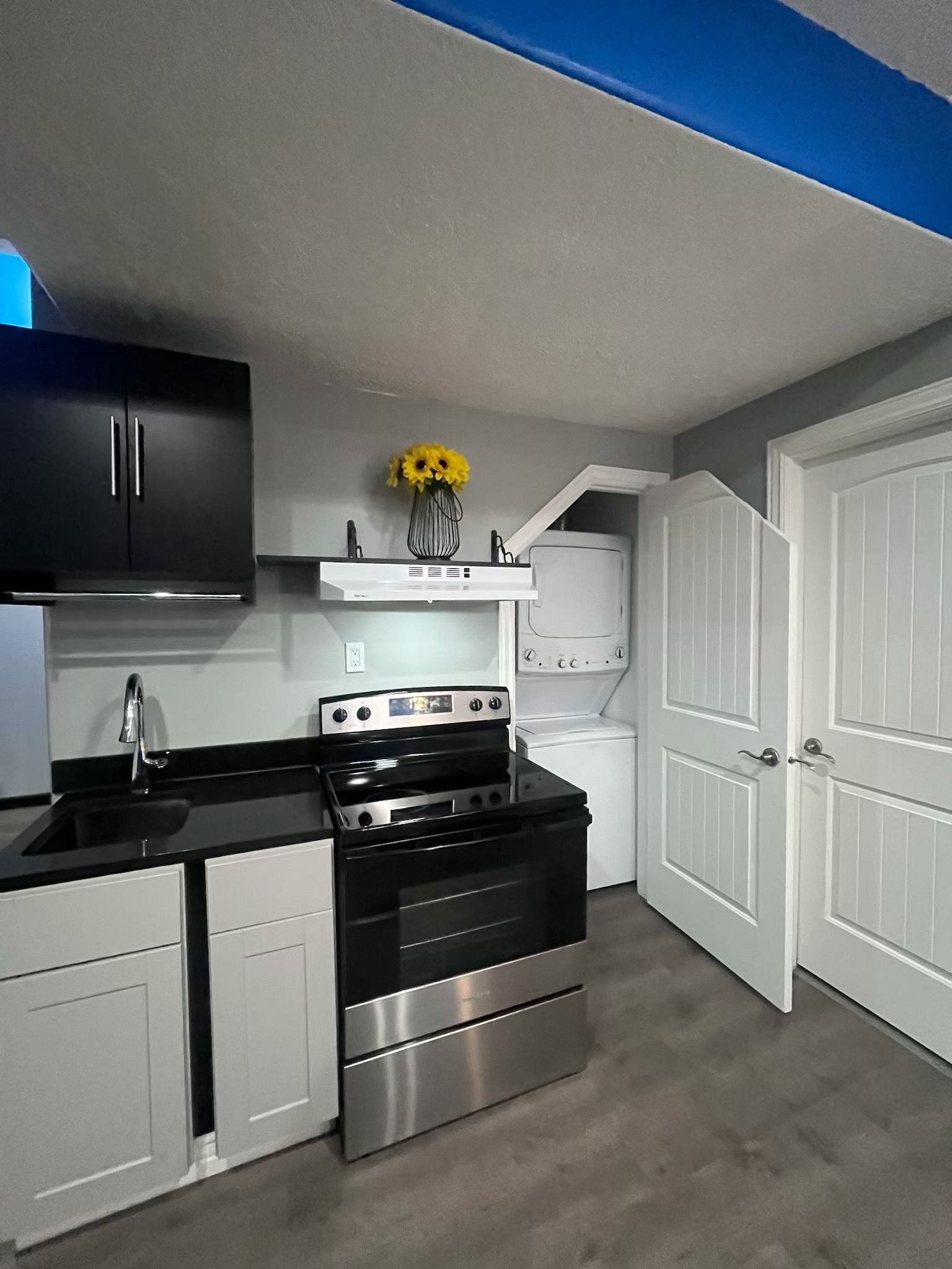 A compact kitchen with a stove, sink, and cabinets.