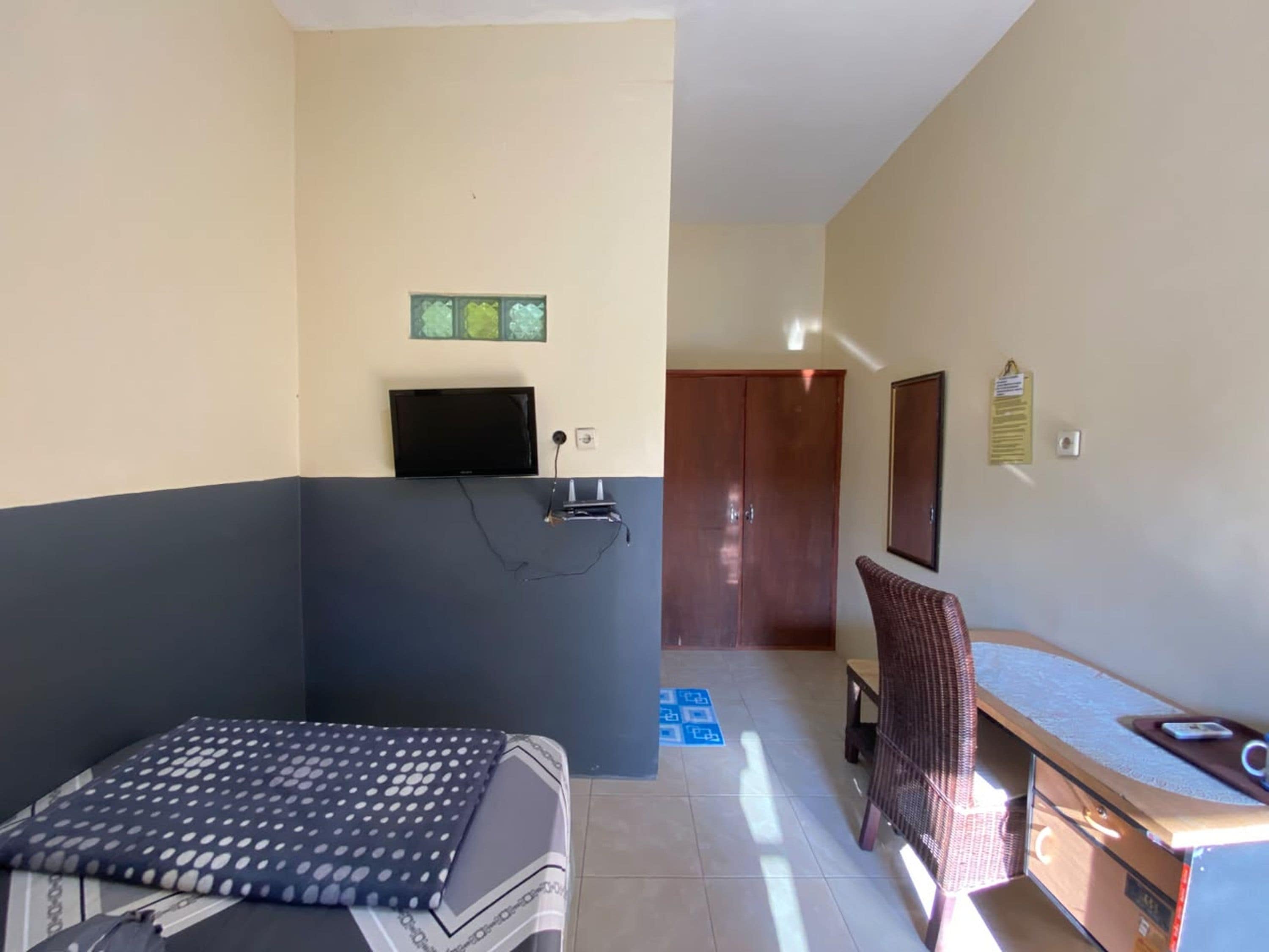 A room with a bed, a desk, a chair, a television, and a wardrobe.
