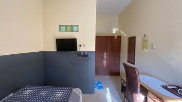A room with a bed, a desk, a chair, a television, and a wardrobe.