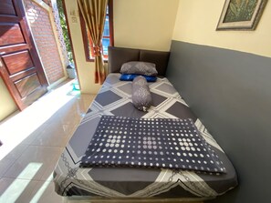 A bed with patterned bedding, a pillow, and a blanket. - Hotel O Wisma Pramuka Syariah (West Cirebon)