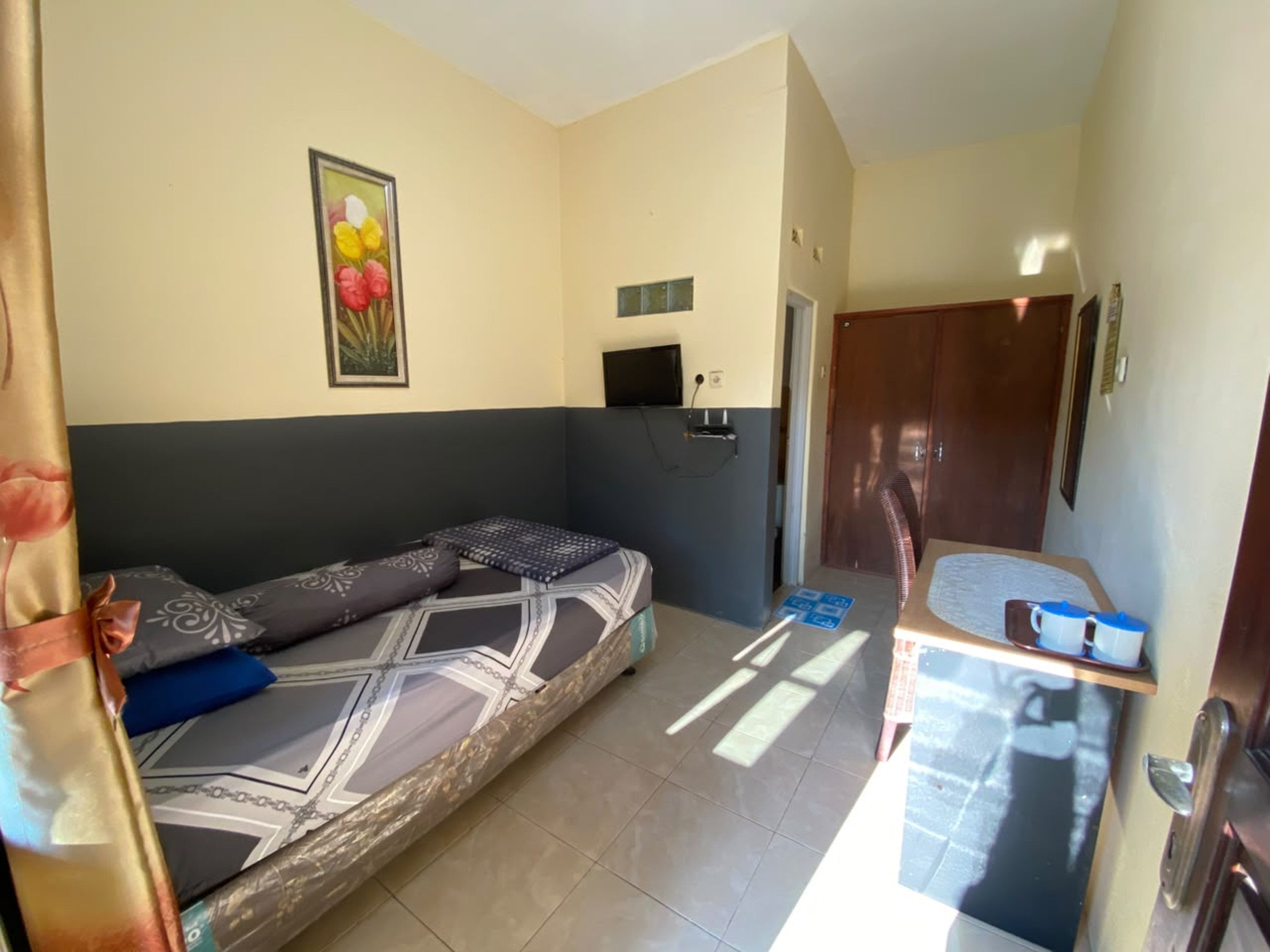 Una habitación con sofá cama, una mesita con tazas, televisión y una puerta.