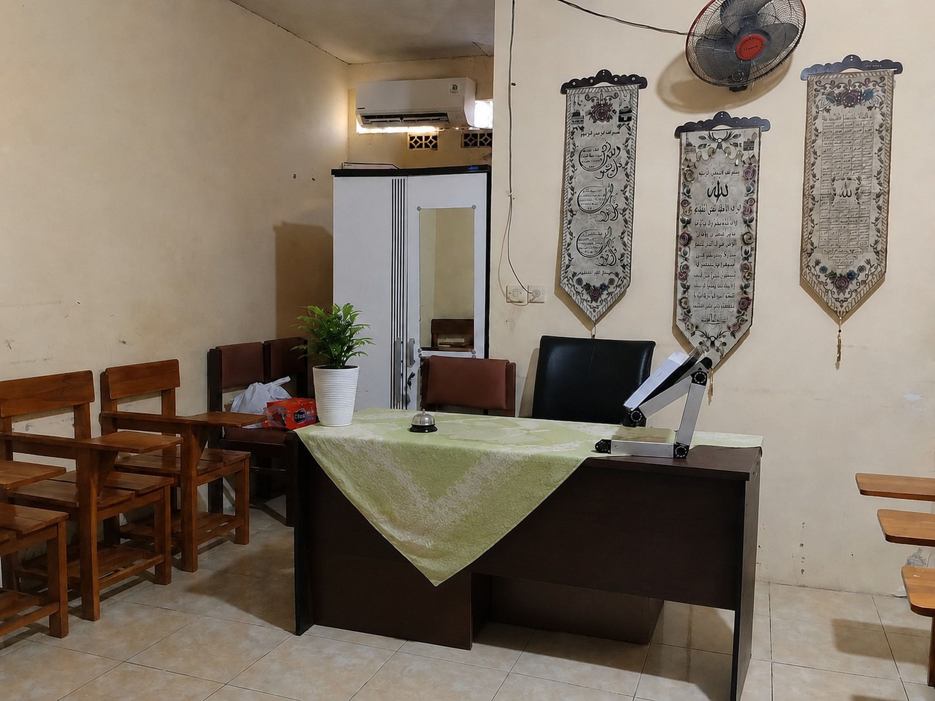 Quarto com escrivaninha, cadeiras, planta em vaso e detalhes decorativos nas paredes.