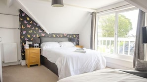 A bedroom with a bed, a nightstand, a dresser, and a window with a view of the outside.