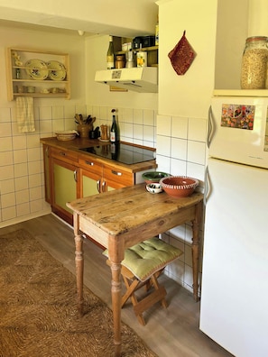 A kitchen with a wooden table, a green bowl, and a white refrigerator. - Country house with wild garden and field views (Vig)