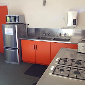 A compact kitchen with a refrigerator, double sink, and gas stove.