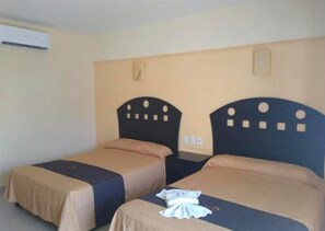 A room with two beds, each with a headboard and a bedspread. There is a wall-mounted air conditioning unit above the beds. - Hoteles Guru Xi Mar (Acapulco de Juárez)