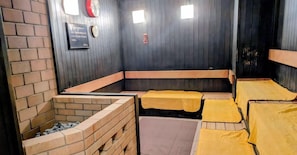 A room with brick walls, wooden benches, and yellow beds.