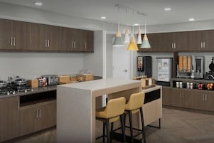 A modern kitchen with wooden cabinets, a central island with bar stools, and pendant lighting.