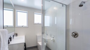 A modern bathroom with a glass shower enclosure, a white sink, and a toilet. - Asure Dunedin Academy Court Motels (Dunedin)