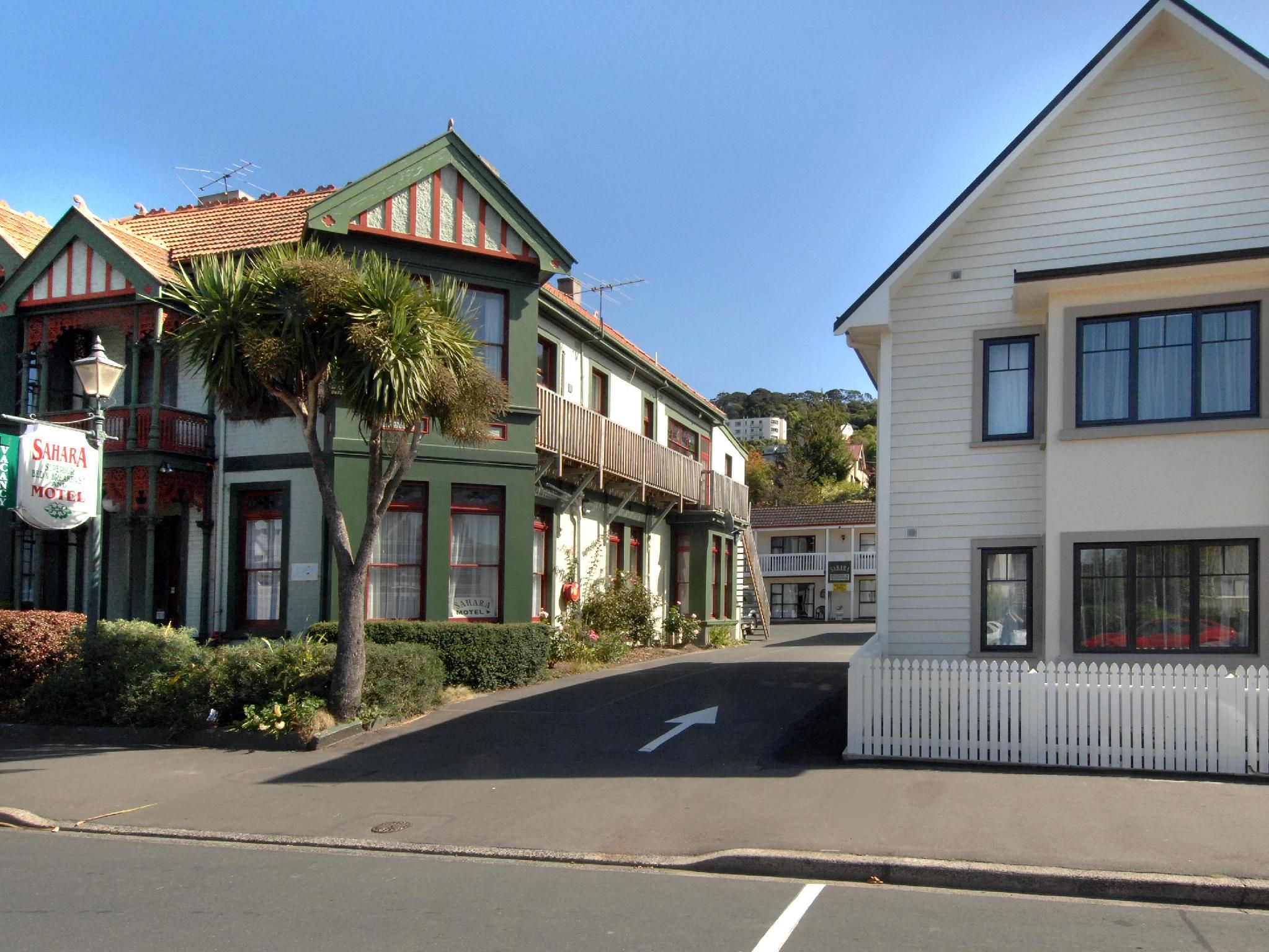 A street with a green and white building with a sign for Sahara Motel.