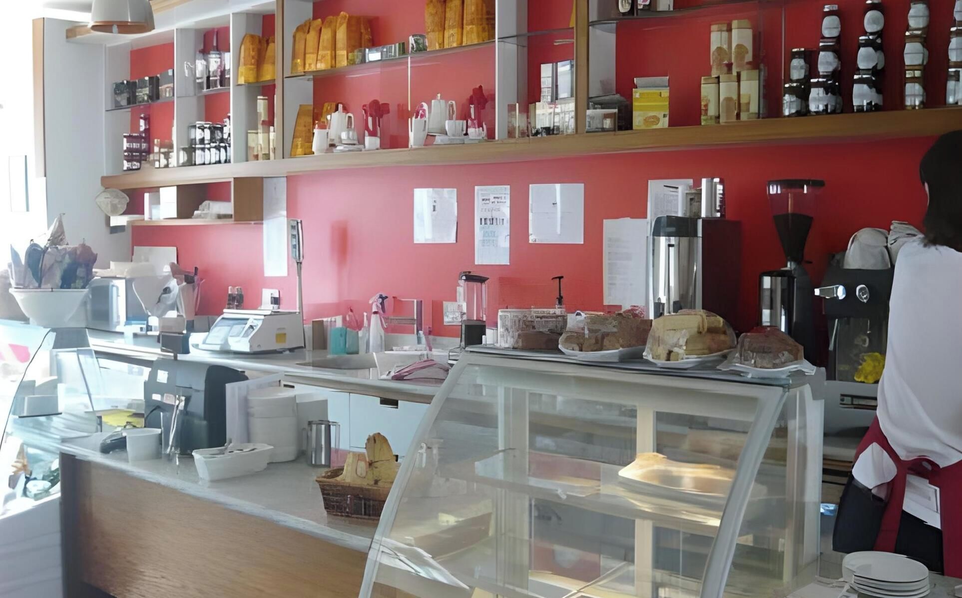 Eine Bäckereitheke mit verschiedenen Backwaren, einer Kaffeemaschine und einer Kasse.