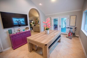 A modern living room with a wooden dining table, a pink cabinet, a TV, and a home gym. - 3 Bedroom/2 Bathroom Lake Park Long Pond Oasis (Lake Park)