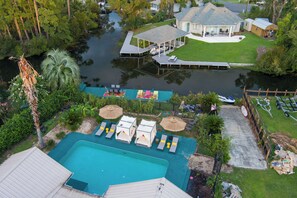 Ein Wohnhaus mit Schwimmbad, überdachter Terrasse und einer Anlegestelle, die ins Wasser ragt.
