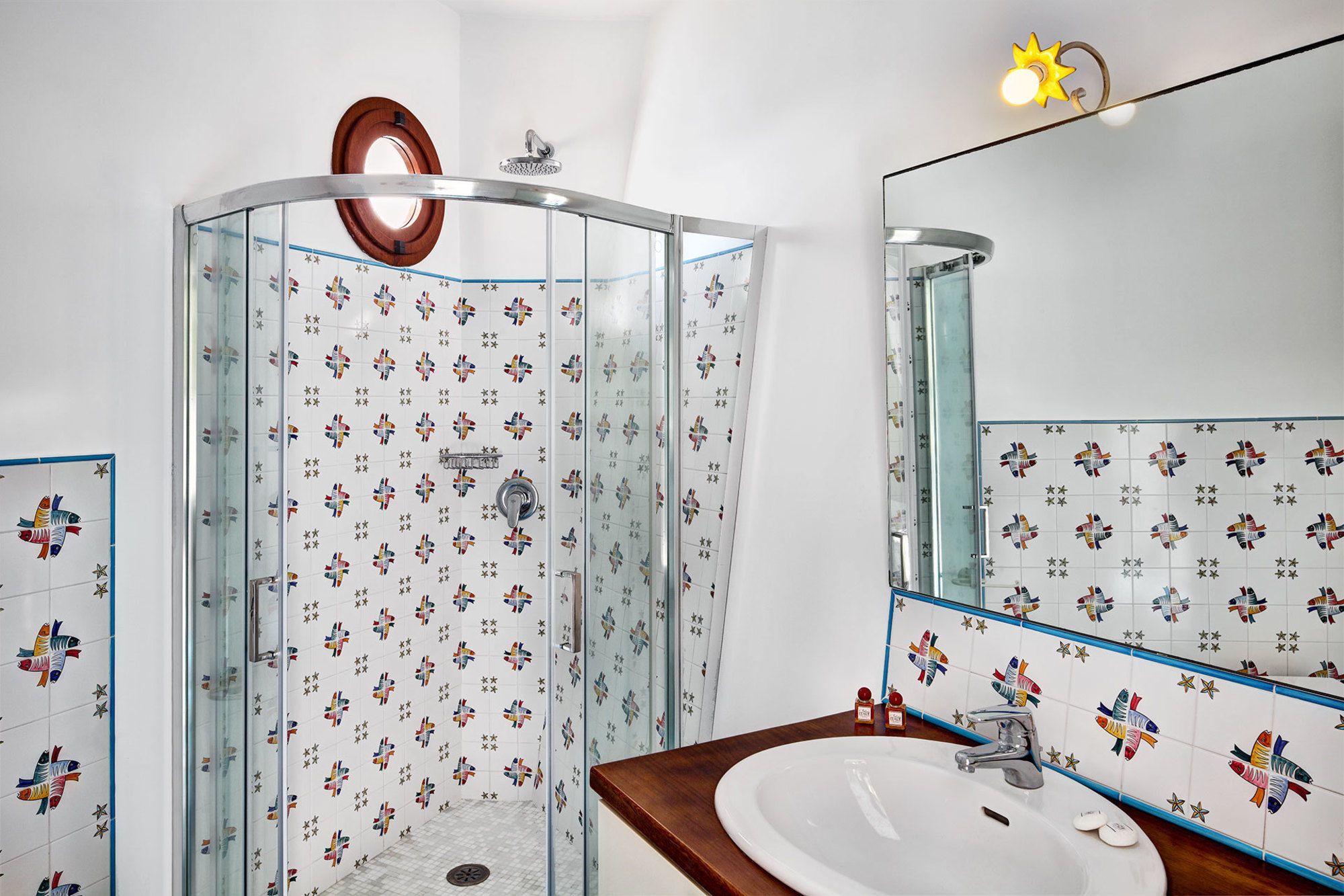 Un bagno con box doccia in vetro, lavandino e specchio.