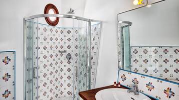Un bagno con box doccia in vetro, lavandino e specchio.