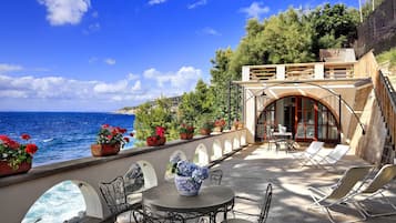 Una terrazza con vista sul mare, arredi da esterno e piante in vaso.