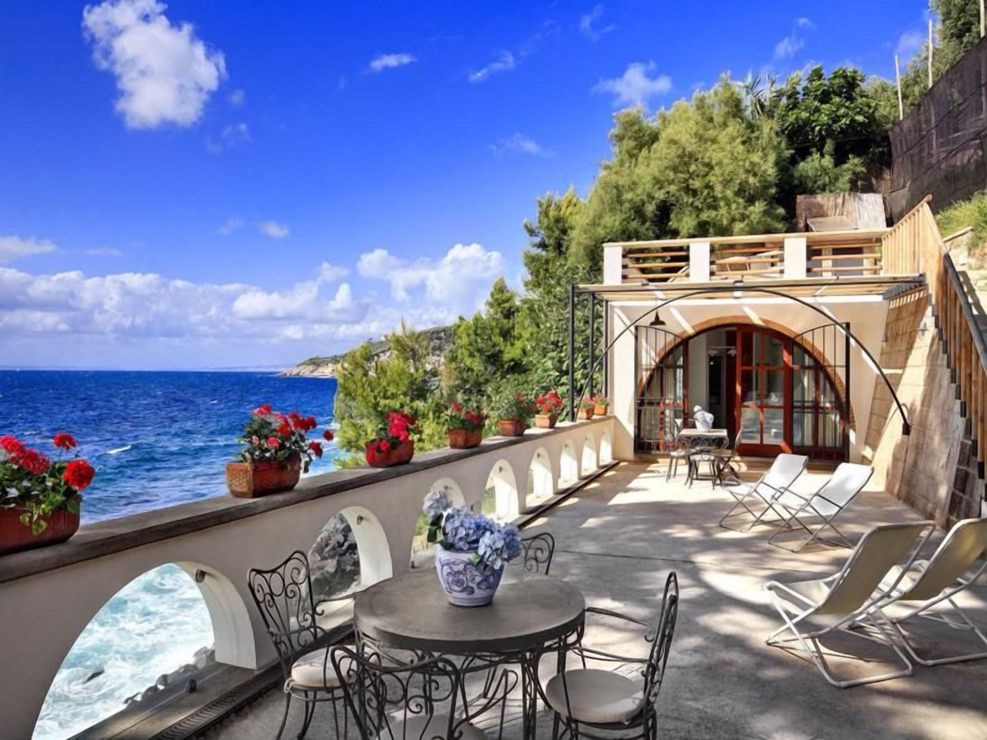 Una terrazza sul mare con zona pranzo, posti a sedere all'aperto e vista mare.