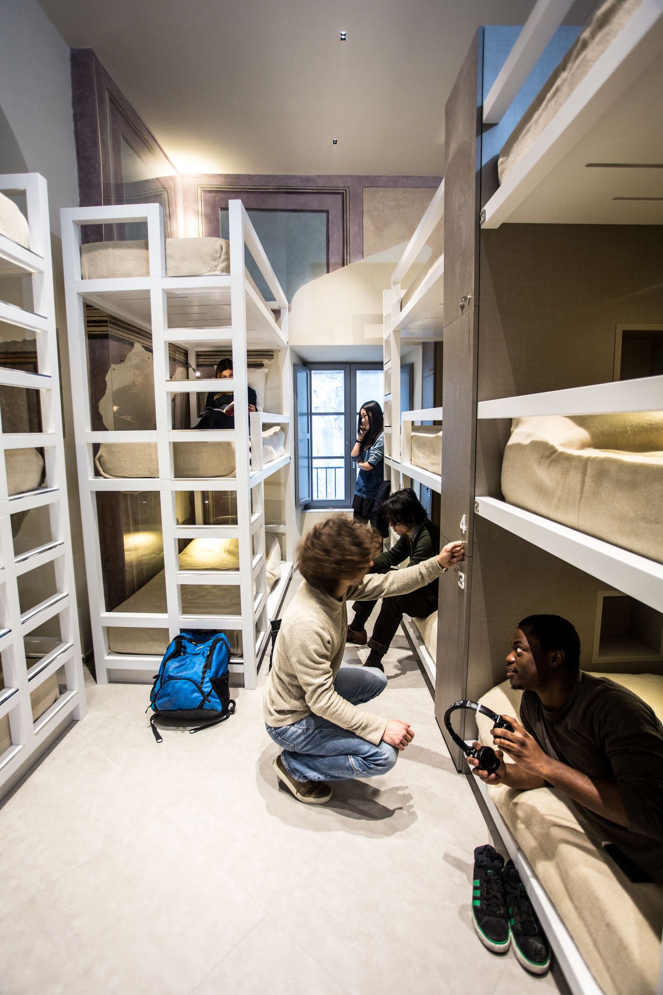 A room with bunk beds, a blue backpack, and a person holding a camera.