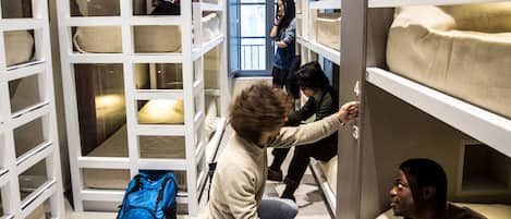 A room with bunk beds, a blue backpack, and a person holding a camera.